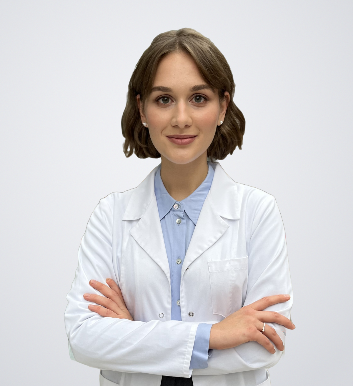 iDerma dermatovenerologijos gydytoja rezidentė Eglė Rugienė baltu chalatu šviesiai pilkame fone.